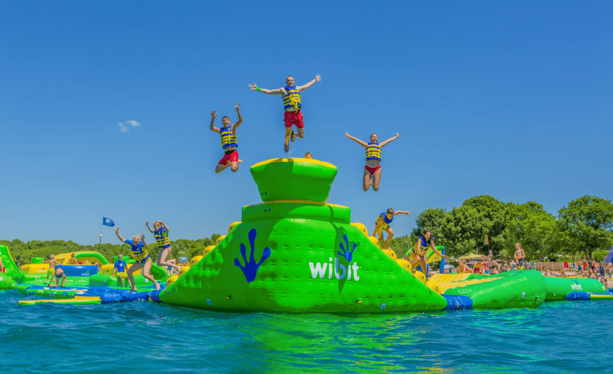 Jumping at inflatable waterpark on sunny lake with blue skies