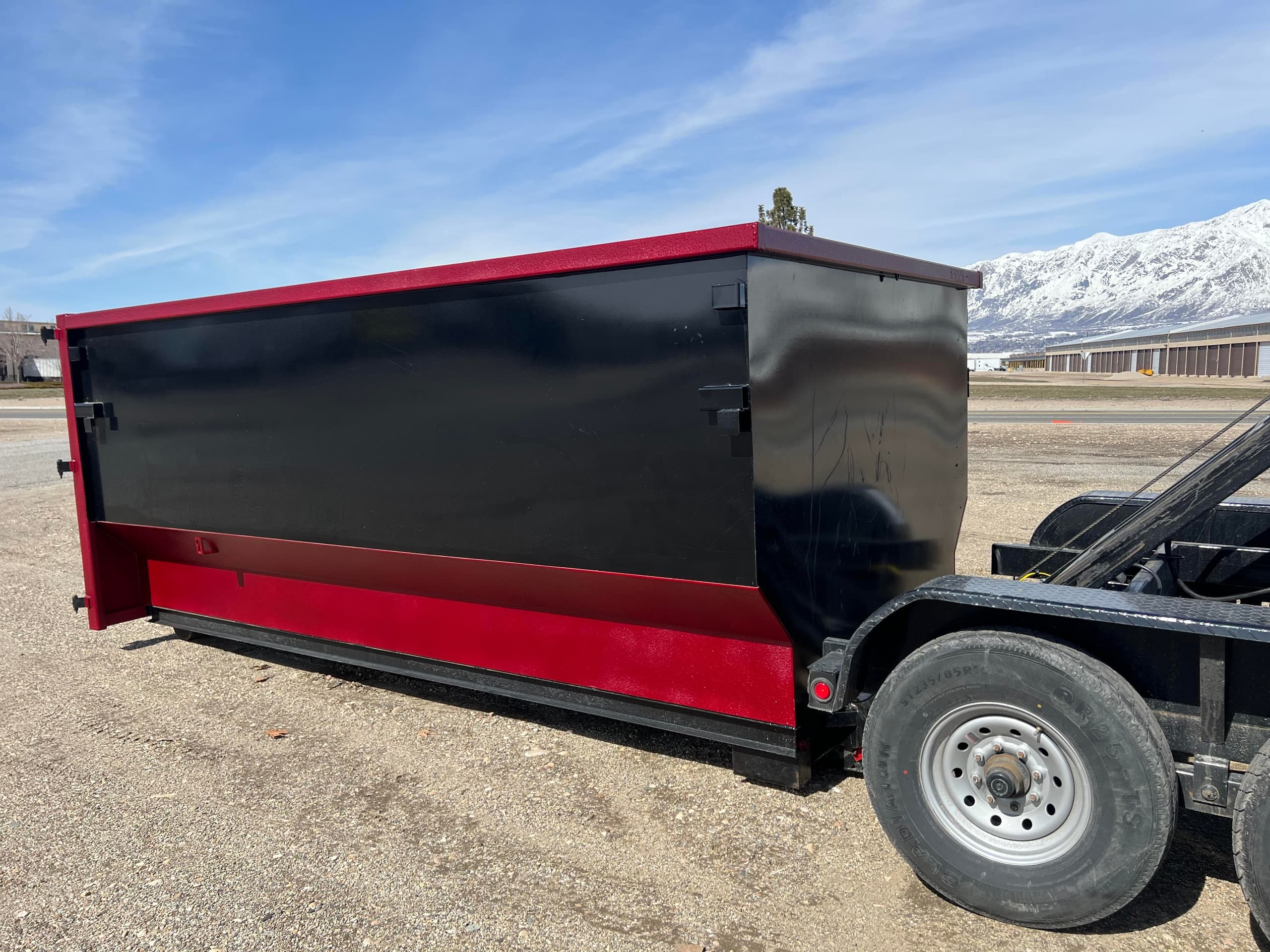 Roll-off dumpster on trailer by snowy mountain landscape