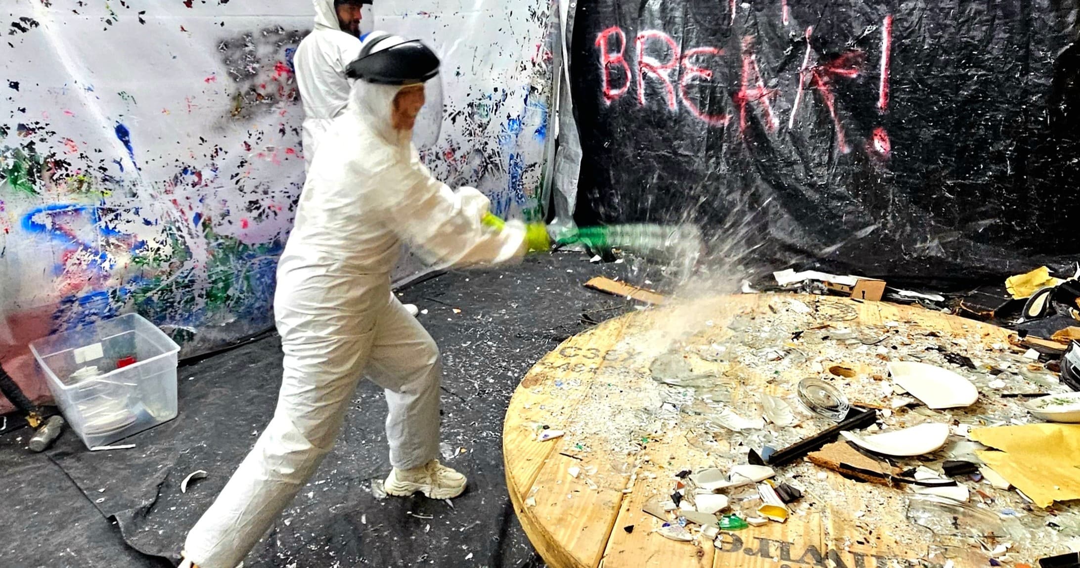 Person in protective suit smashing objects in indoor studio