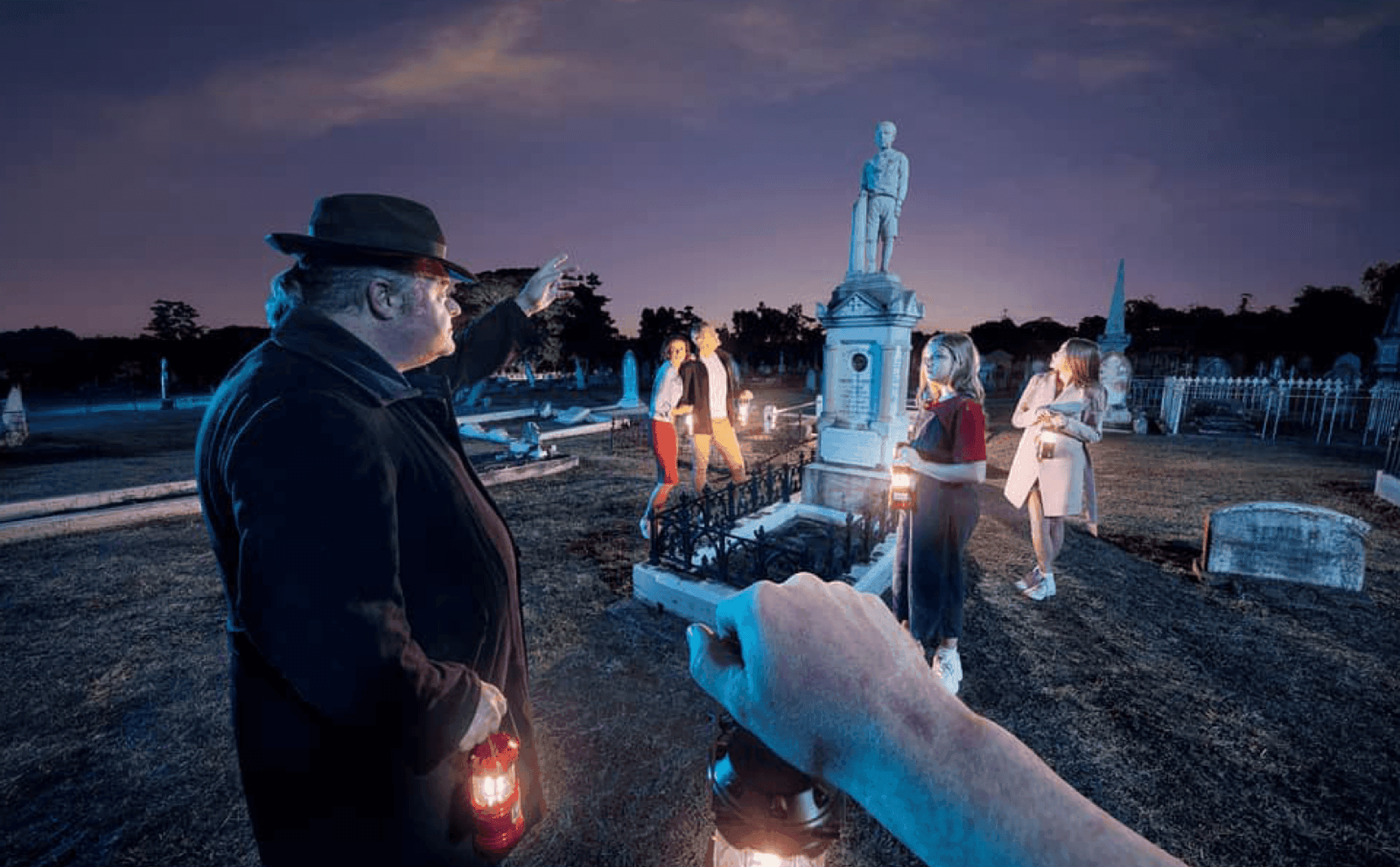 Night cemetery lantern tour with guide and participants outdoors