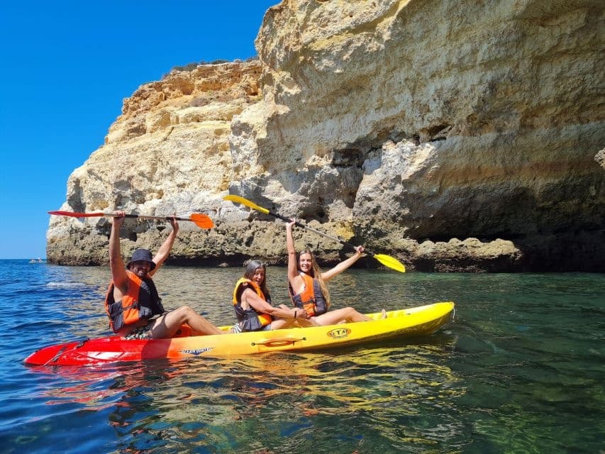 Sea kayakers paddling near coastal limestone cliffs, clear water