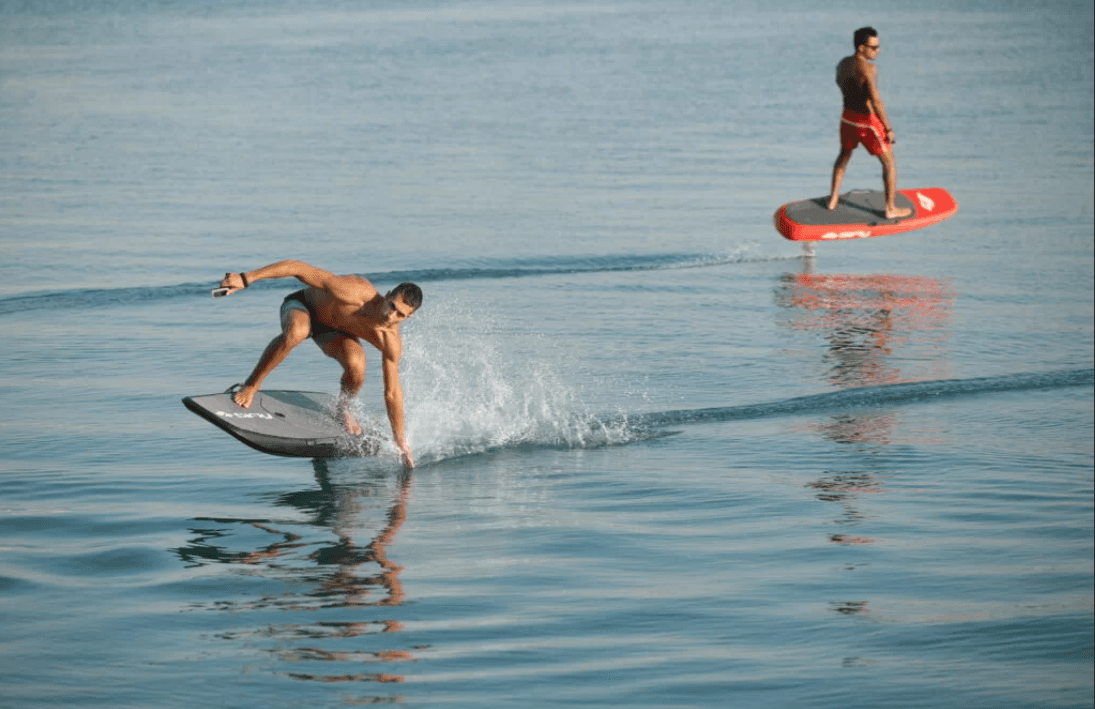 Foil surfing on calm coastal ocean with riders carving