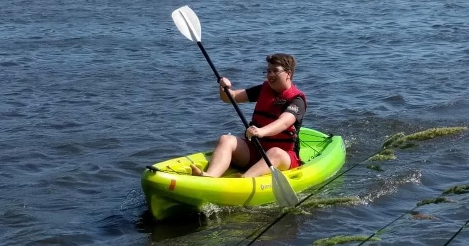 Solo kayaker paddling on open water near shoreline