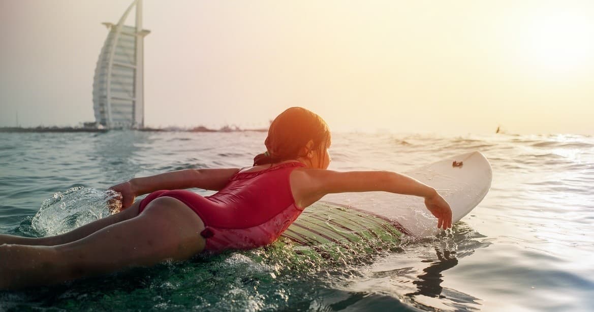 Paddler on surfboard at golden sunset with shoreline skyline vista