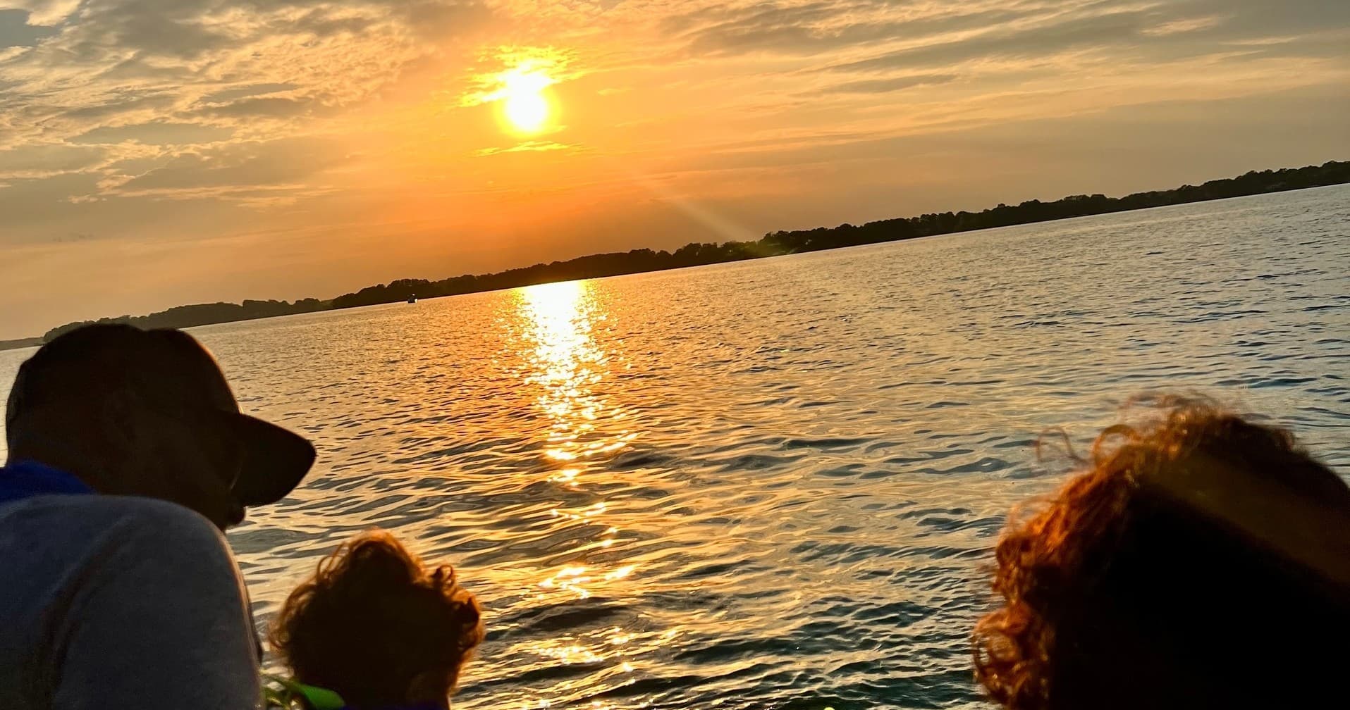 Sunset boat cruise silhouettes on calm lake horizon