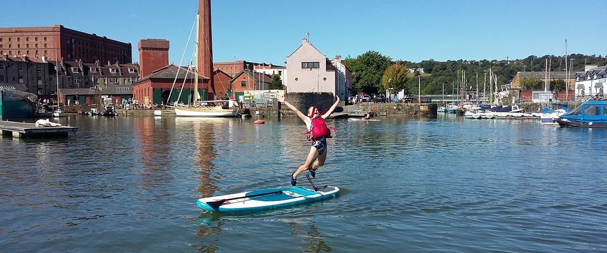Solo stand-up paddleboarder cruising through marina basin
