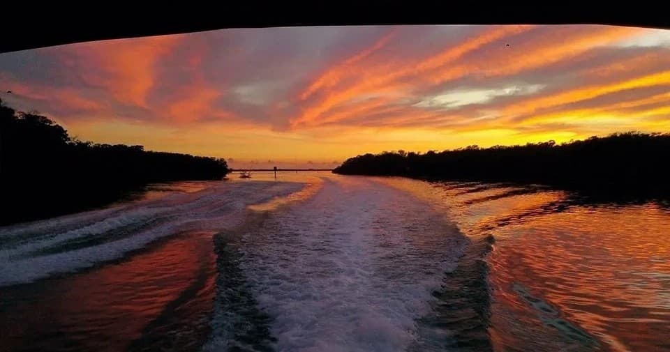Boat wake cutting through coastal inlet at colorful sunset, Florida