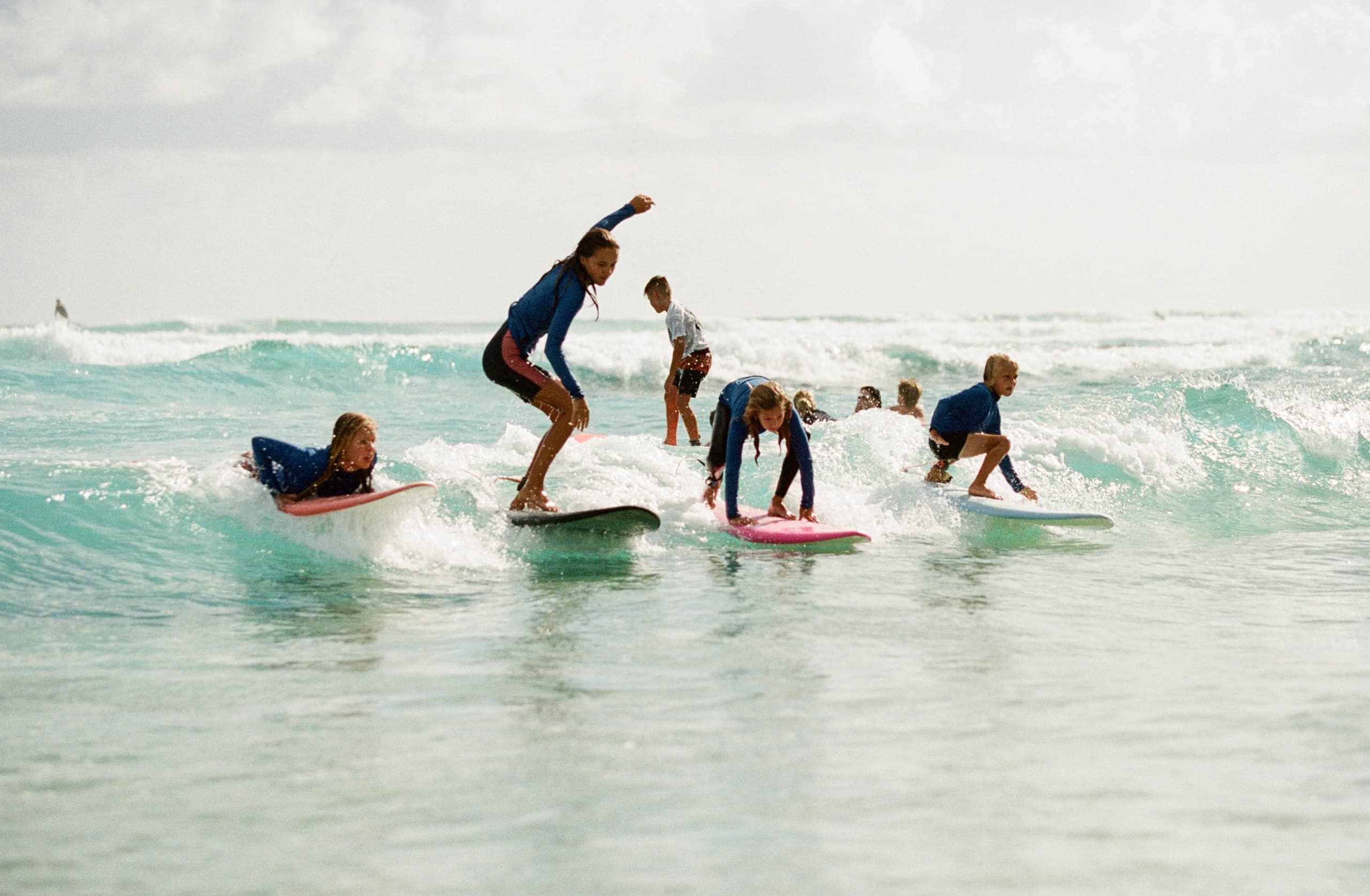 Group of kids learning to surf on shallow Kirra Point waves