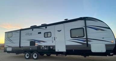 Exterior profile of travel trailer parked on lot for rental listing