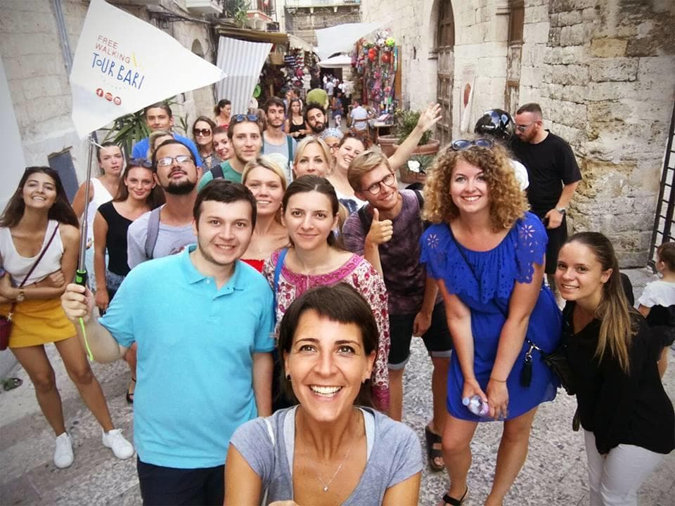 Smiling tour guide selfie with large walking tour group in Bari