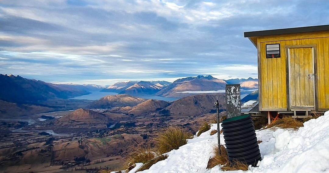 Remote alpine hut above snowy valley, backcountry mountain shelter