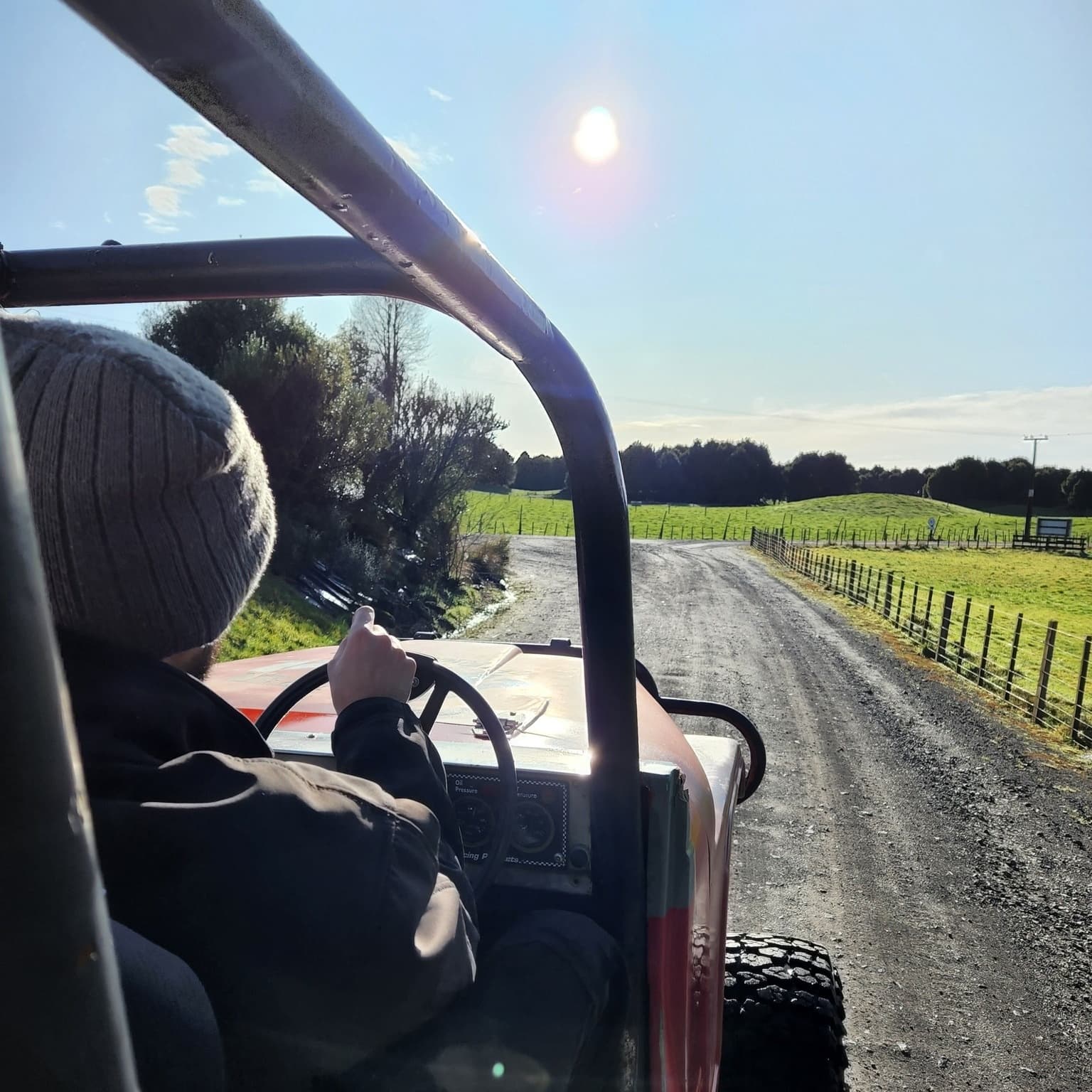 Driver POV in open 4x4 on rural dirt road past farmland