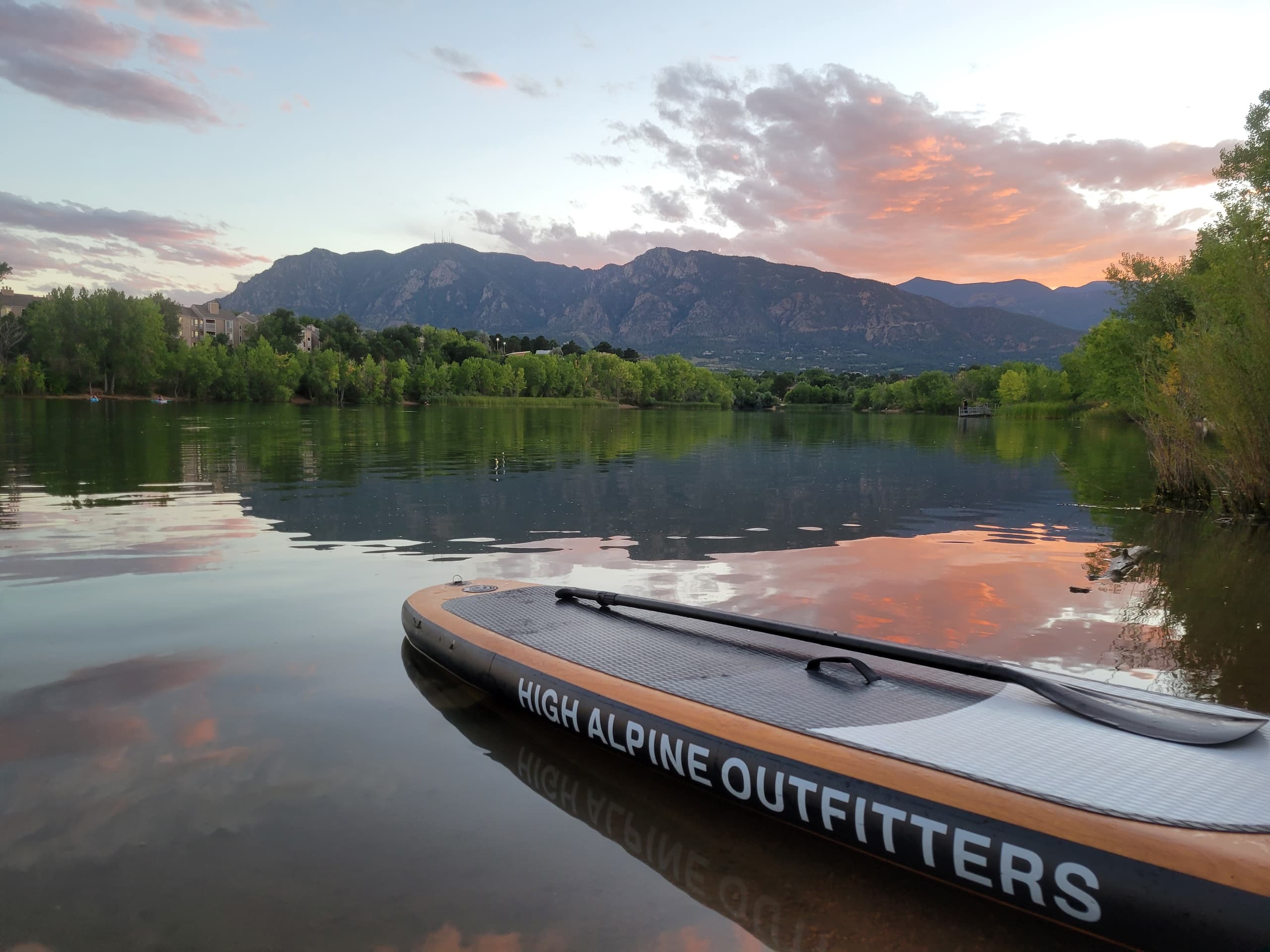 Stand-up paddleboarding on alpine lake at sunset with mountain views