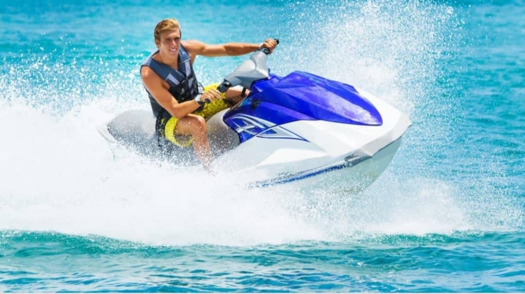 Rider jet skiing on turquoise ocean water near coastline