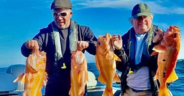 Anglers holding rockfish aboard Pacific charter boat at sea