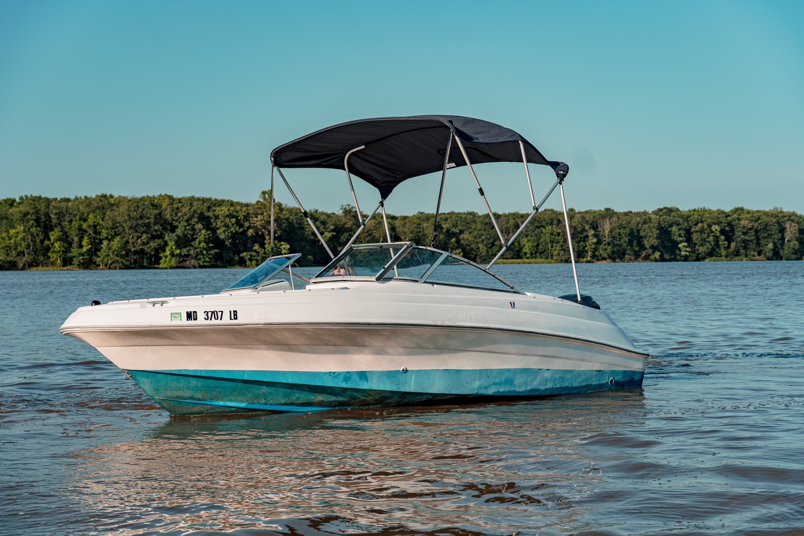 Motorboat anchored on a calm lake with forested shoreline