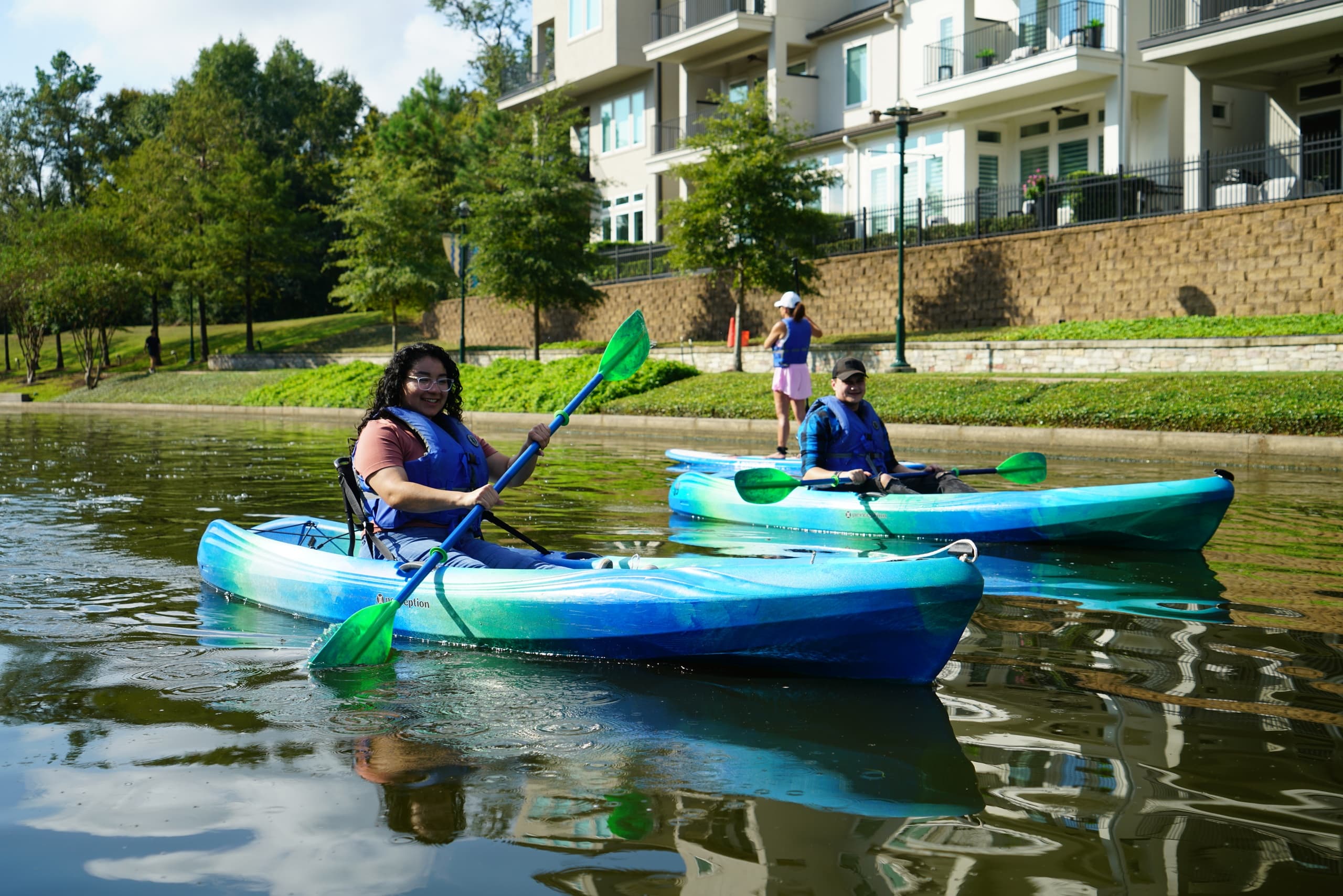 Pair of kayakers paddling near shoreline in urban lake park
