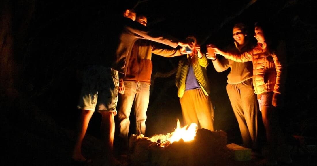 Friends gathered around campfire at night outdoors