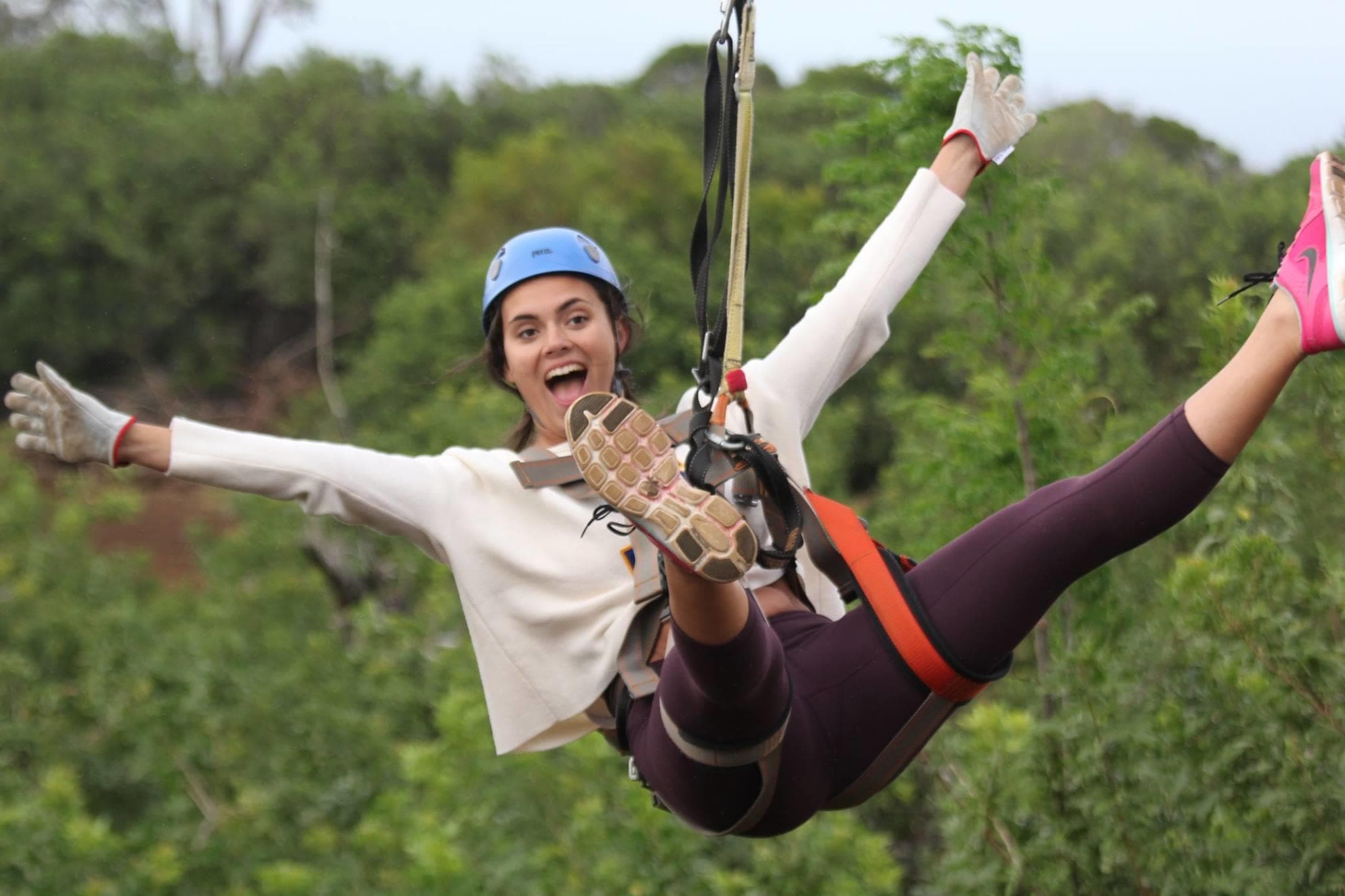 Woman ziplining over lush forest canopy, joyful flight