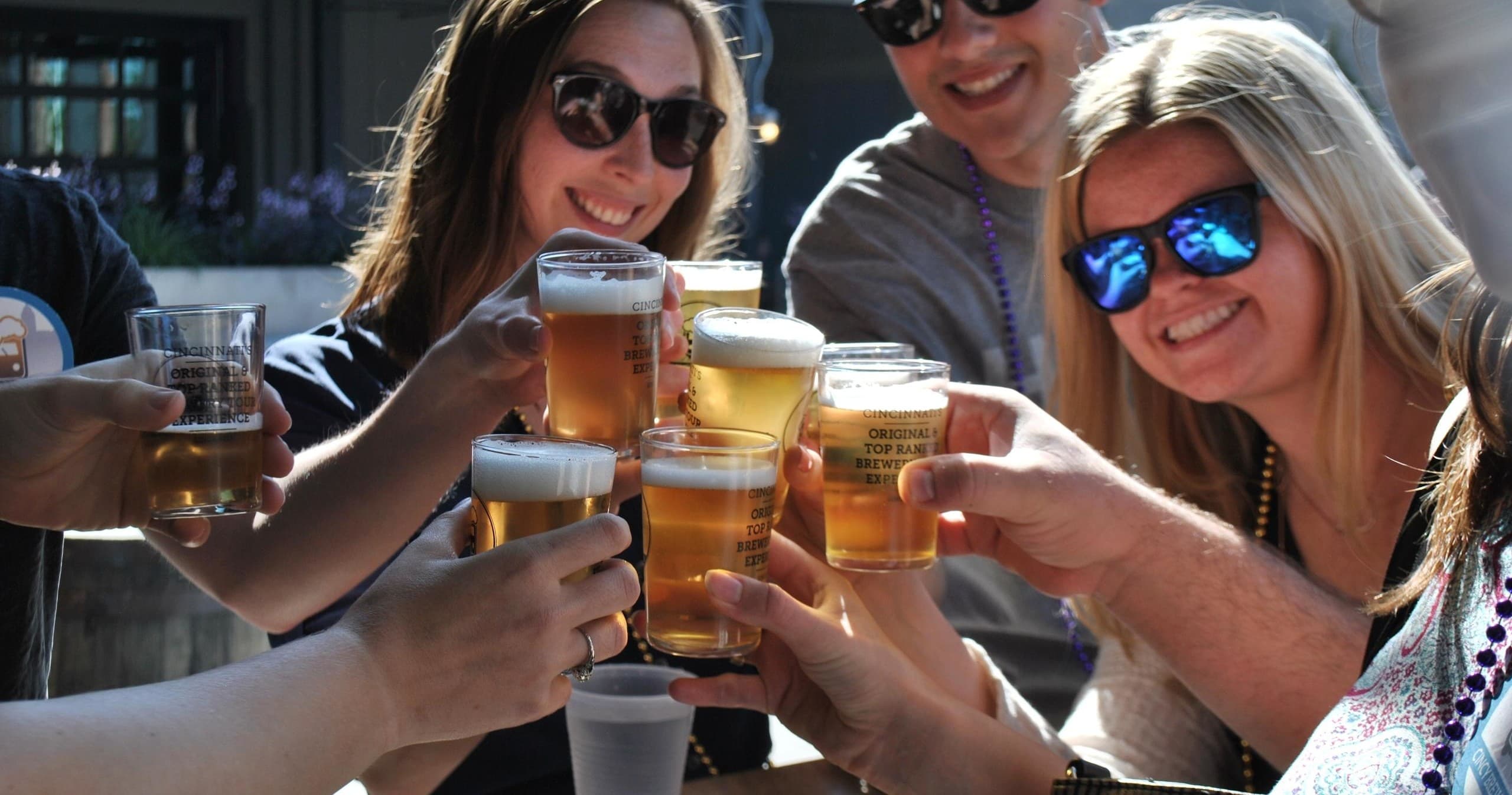 Group toasting craft beers outdoors on sunny brewery patio