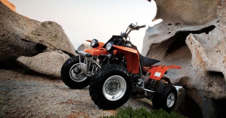 Red ATV parked among boulders in rocky desert landscape