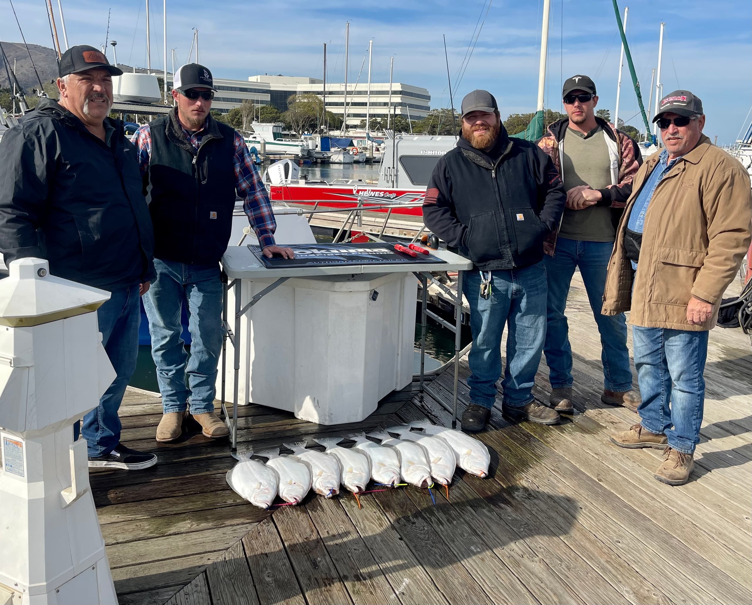 Anglers with lined up flatfish on marina dock after fishing trip