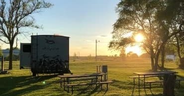 Riverside campsite with RV and picnic tables at golden sunset