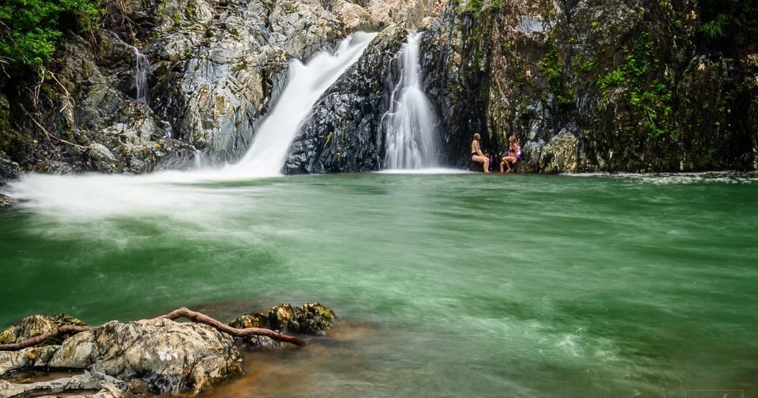 People swimming at emerald waterfall pool in Daintree rainforest