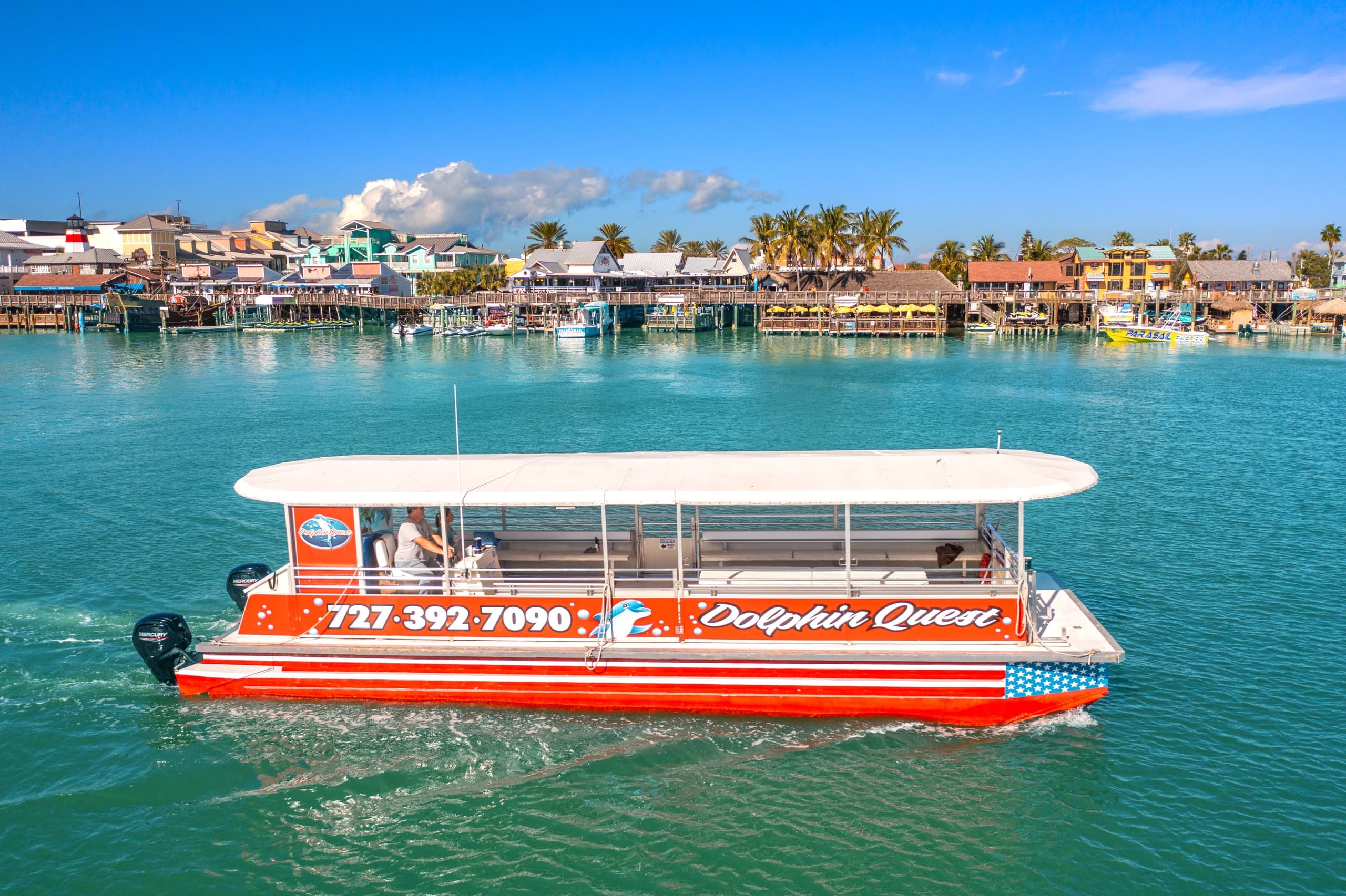 Red dolphin cruise boat near waterfront with island skyline