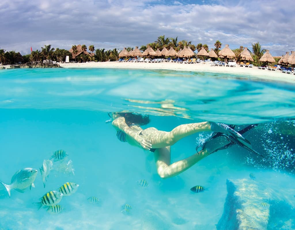 Snorkeler exploring turquoise lagoon with tropical beach resort
