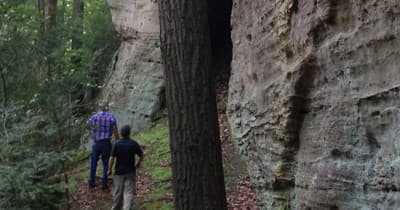 Hikers walking between mossy rock cliffs in forest gorge
