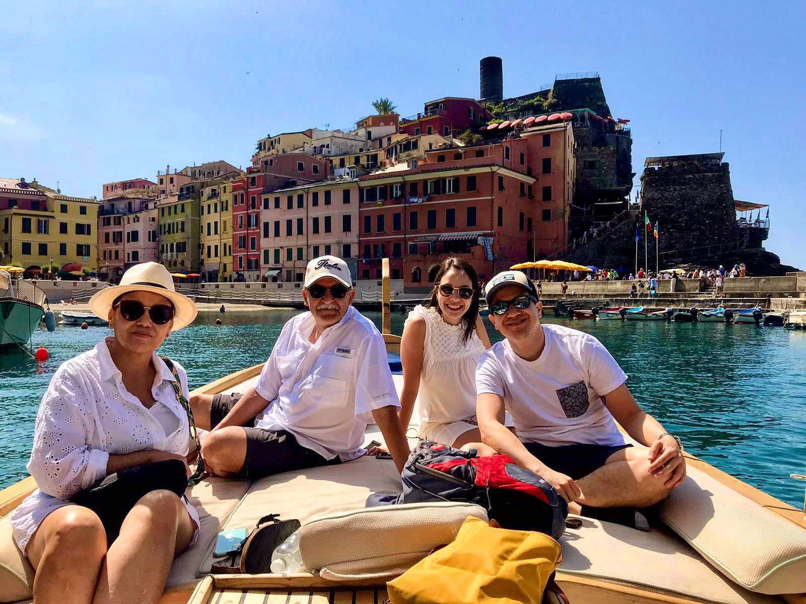 Tourists relaxing on a boat with colorful Cinque Terre village backdrop