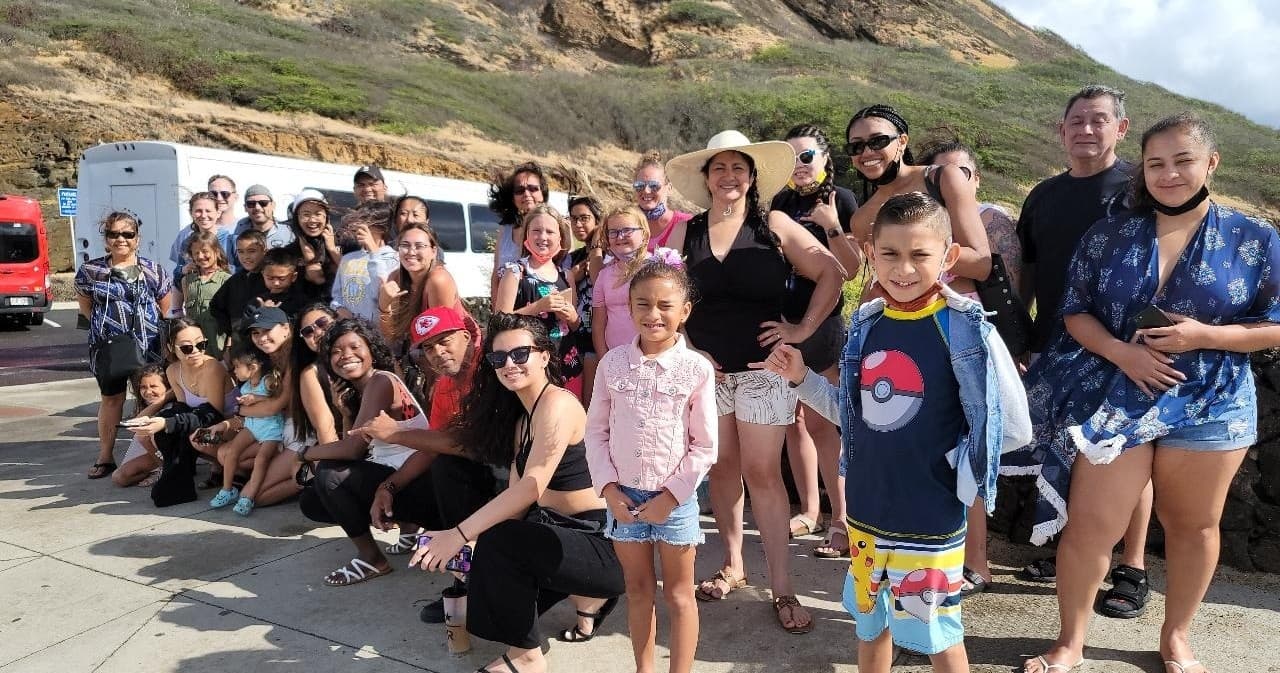 Large mixed-age tour group gathered at coastal overlook on road
