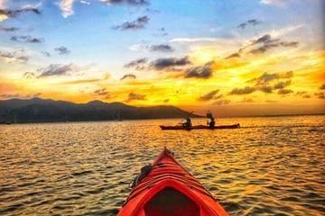 POV red kayak heading toward golden sunset on open sea