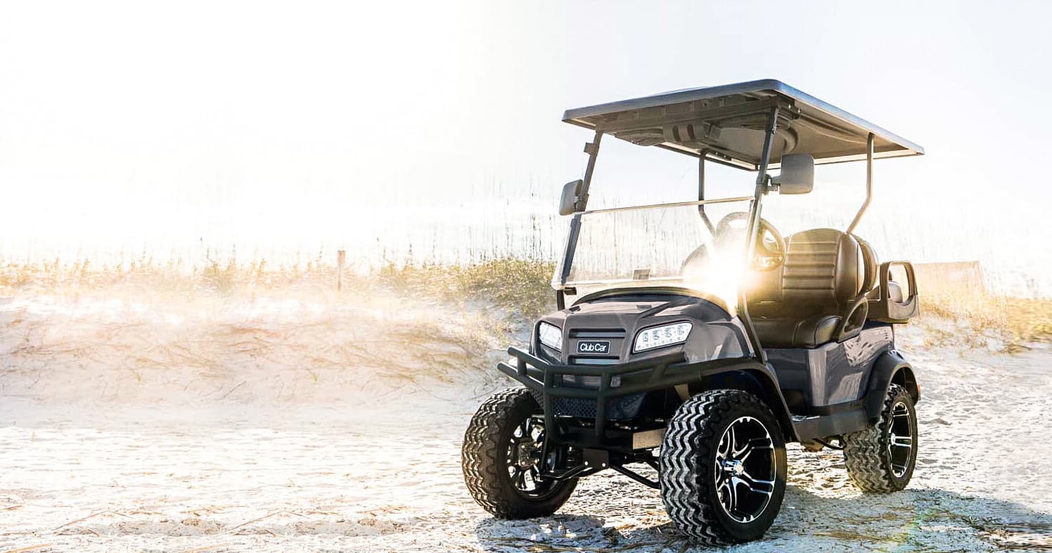Off-road utility cart parked on sandy beach with sunrise