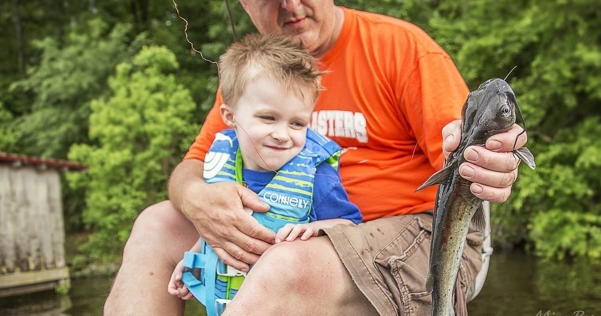 Family fishing catch: father and child holding catfish