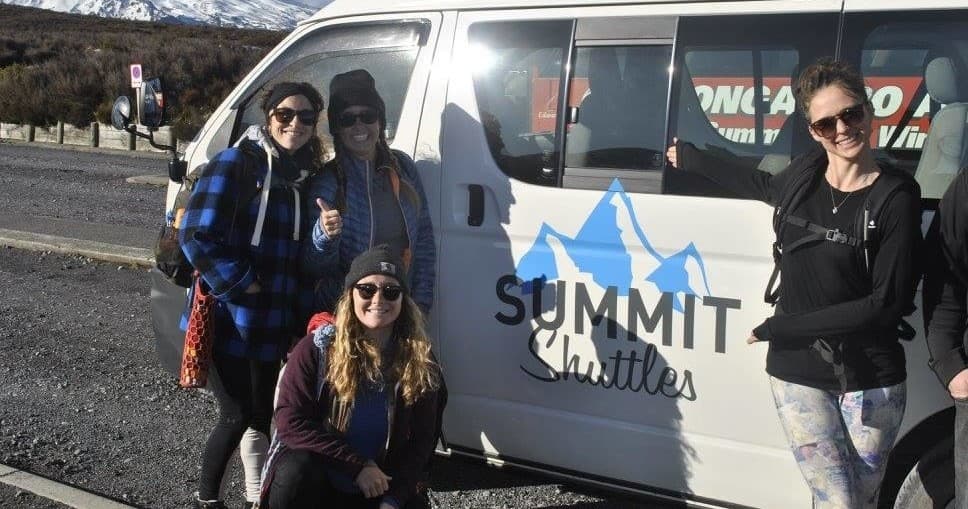 Group of hikers posing beside Summit Shuttles van outdoors