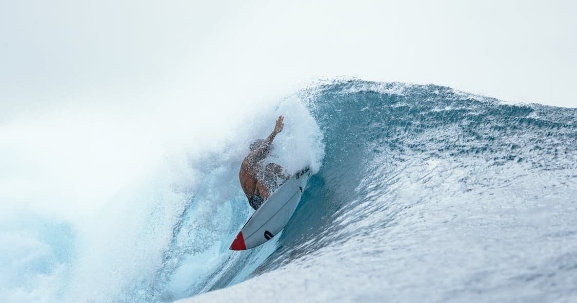Surfer riding a deep barrel wave on open ocean, dramatic tube