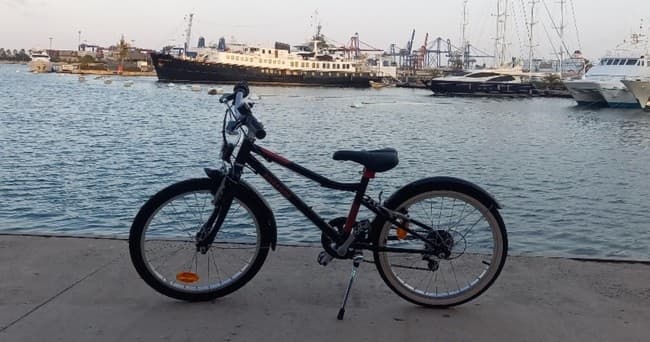 Mountain bike silhouetted on Valencia pier by moored boats