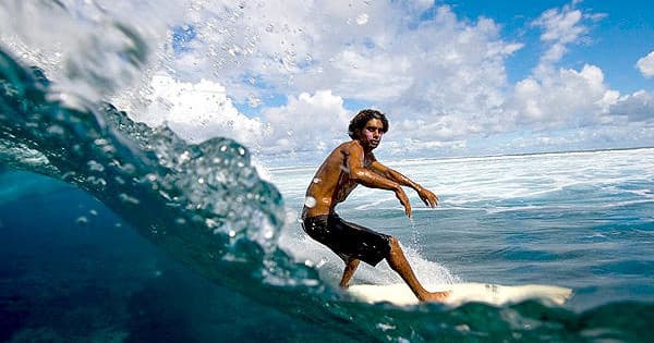 Surfer carving a wave in clear tropical ocean surf