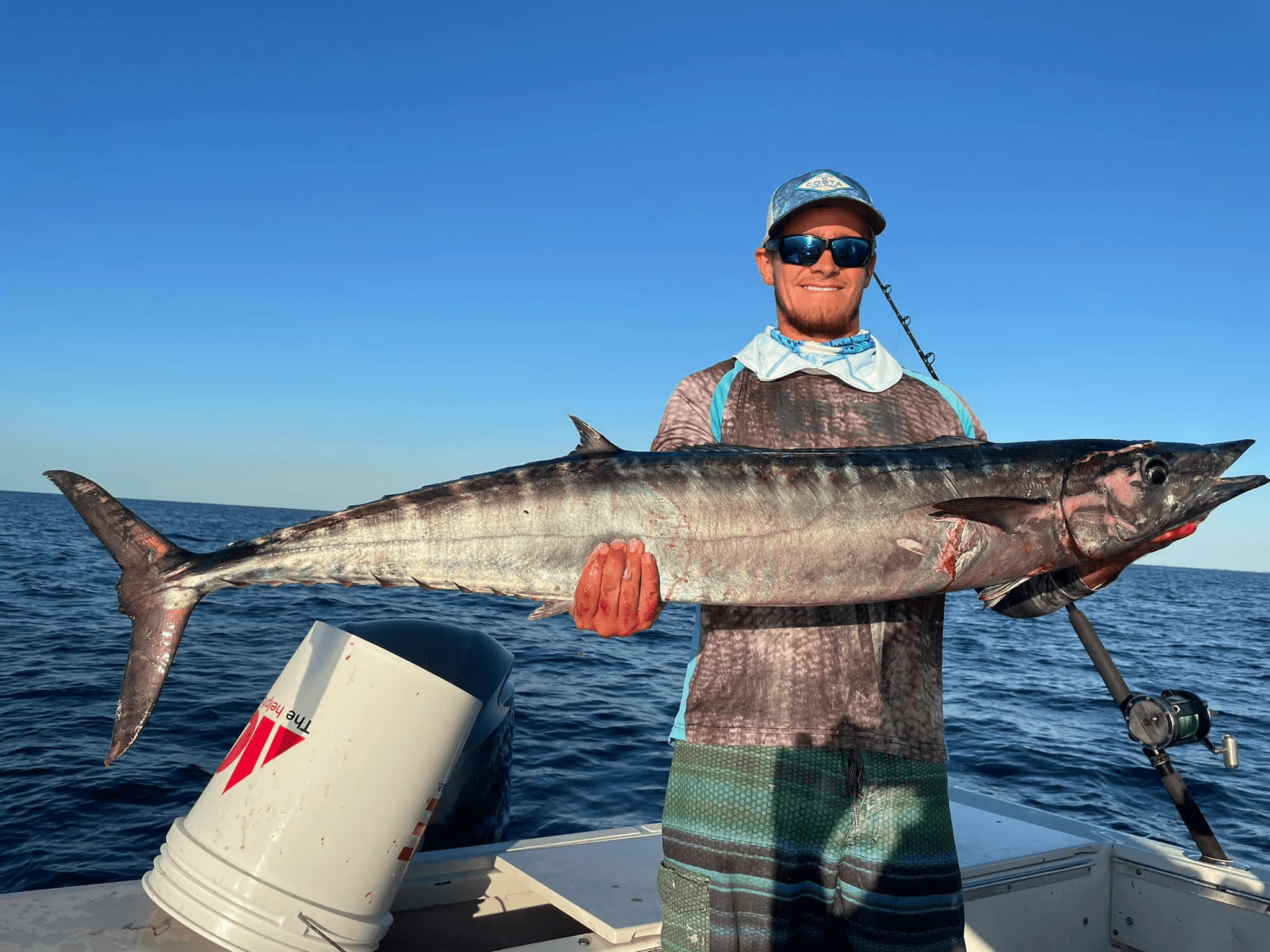 Angler holding a large wahoo offshore on boat, deep-sea fishing