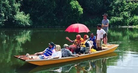 Group river tour on a flatboat with colorful umbrella and guide