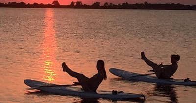 Two kayakers silhouetted paddling during dramatic sunset