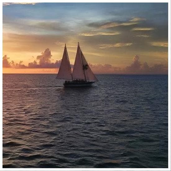 Sailing schooner cruising alone at sunset on open sea