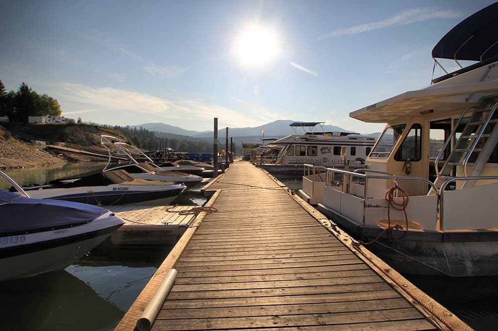 Wooden marina dock leading to boats at sunrise on mountain lake