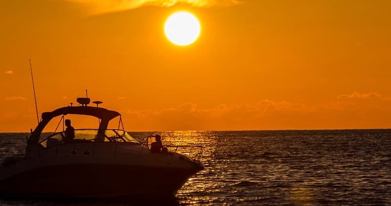 Sunset boat cruise on open ocean with golden horizon