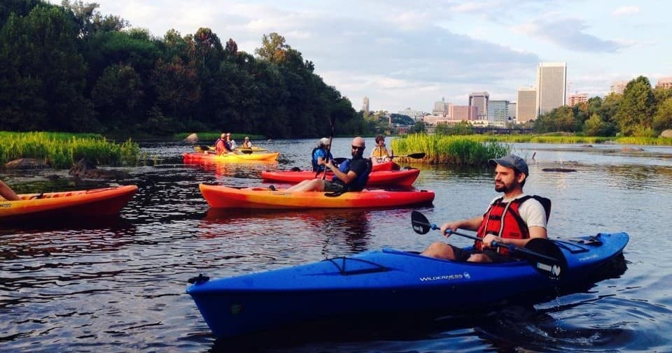 Group kayaking tour on river with urban skyline in background