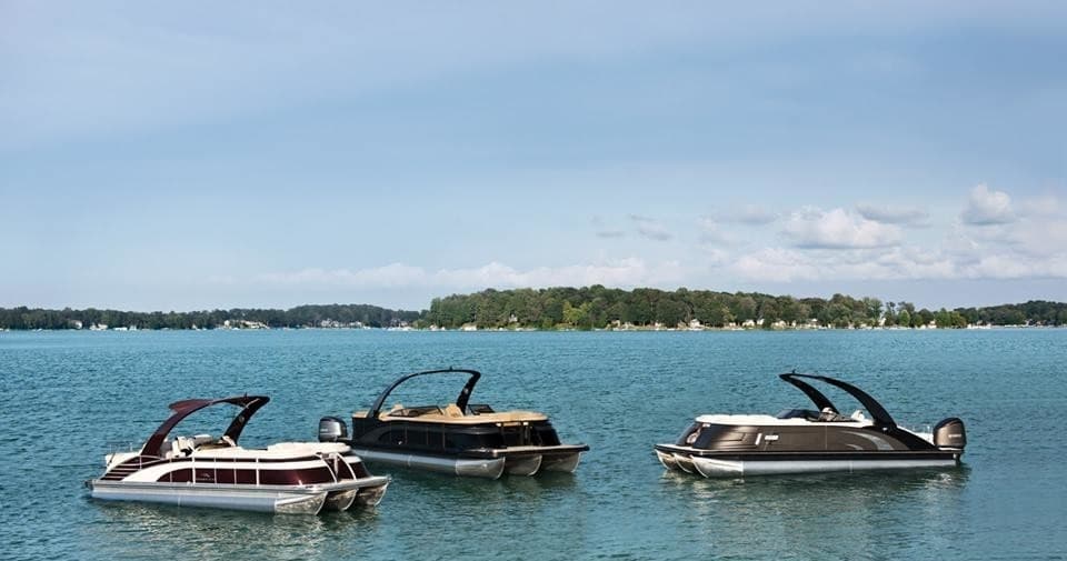 Three pontoon boats drifting on clear blue lake near shore