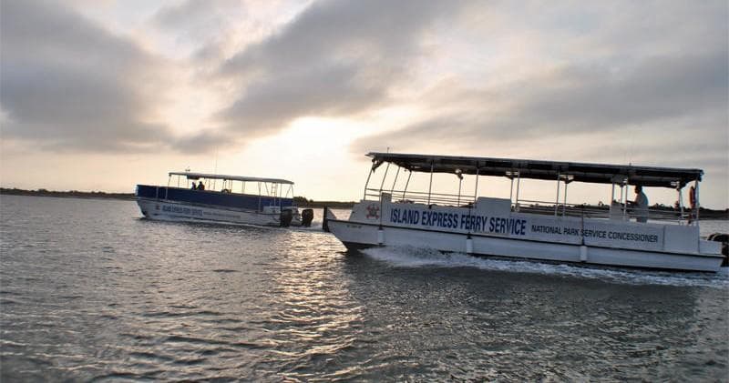 Two ferries gliding across calm bay under dramatic sunset sky