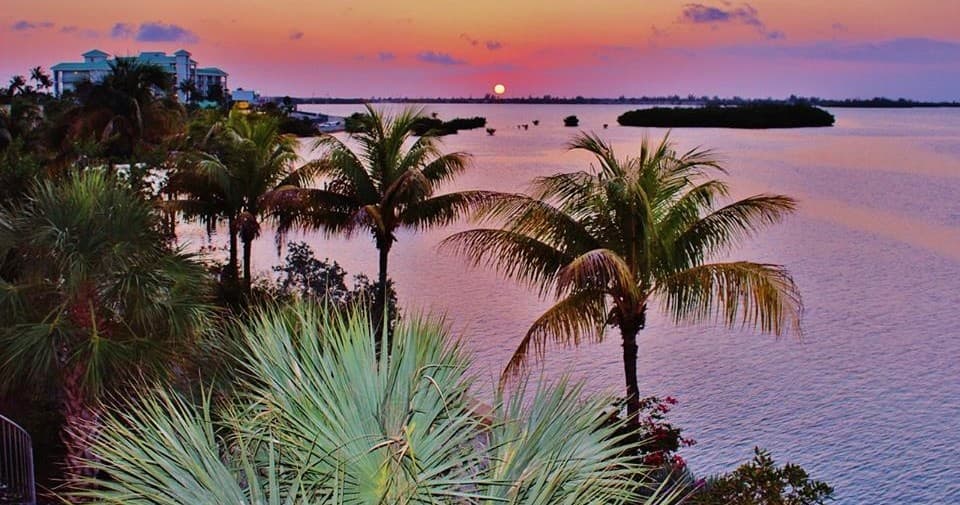 Sunset over Key West waterfront with palm trees and islands